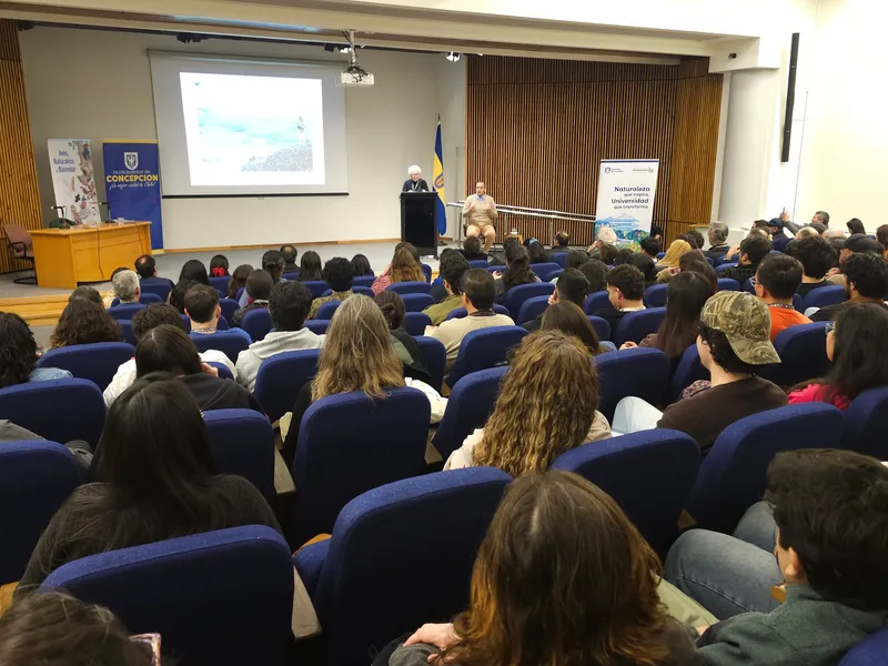 Auditorio lleno durante la conferencia inaugural, con una persona en el podio y un intérprete de lengua de señas.